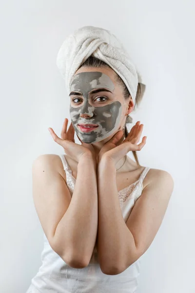 pretty sexy woman applying clay black mask on white background. Skin care, spa treatments for perfect skin
