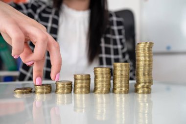 Bozuk para yığınının üzerinde yürüyen kadın parmaklarını kapat. Finansal kar büyümesi kavramı.
