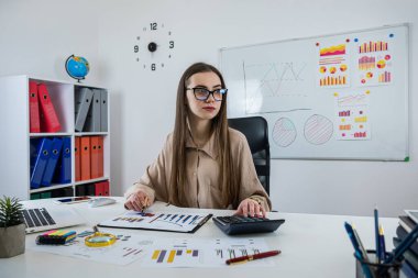 İş kadını, mali sonuçlar ve istatistik şirketi yıllık raporu için dizüstü bilgisayar ve hesap makinesi kullanıyor. Ofis işyeri