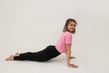 Sportif genç kadın yoga ya da pilates yapıyor. Esnekliğinin izole olduğunu gösteriyor. 
