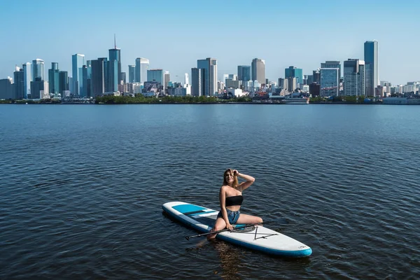 Young women spend time for nature paddles a SUP board on a city lake, summer time for trip