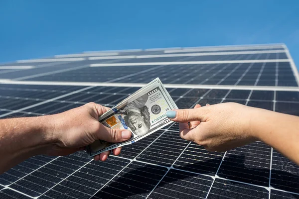 customer gives money to the worker for successfully installing the solar panels. the concept of saving electricity