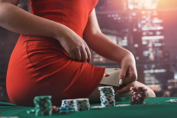 young woman in a casino sits on a poker table with colored chips and seductively hides a card under her dress. poker. women in a man\'s game. deception. casino