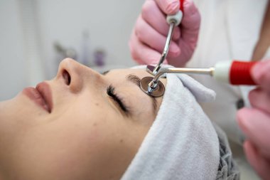 Genç ve güzel bir kadın spa kliniğinde mikroakım tedavisi görüyor. Kırışıklıkların düzeltilmesi için prosedür 