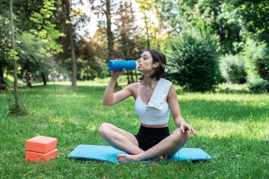 Açık hava parkındaki yeşil çimlerde egzersiz yapan beyaz bir kadın. Sağlık için spor