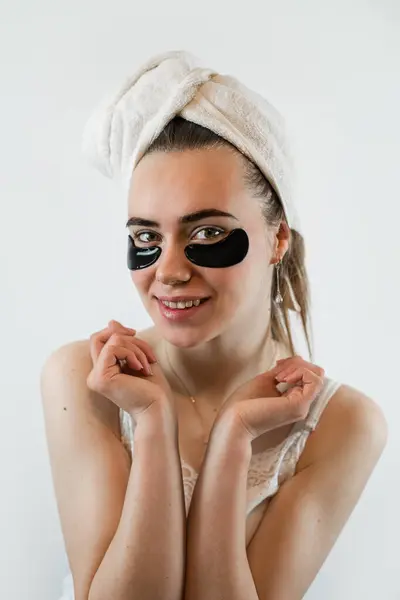 タオルの若い女性は白で隔離された目の下にコラーゲンハイドロゲルの美容パッチを適用します しわのない目のパッチ スキンケアコンセプト — ストック写真