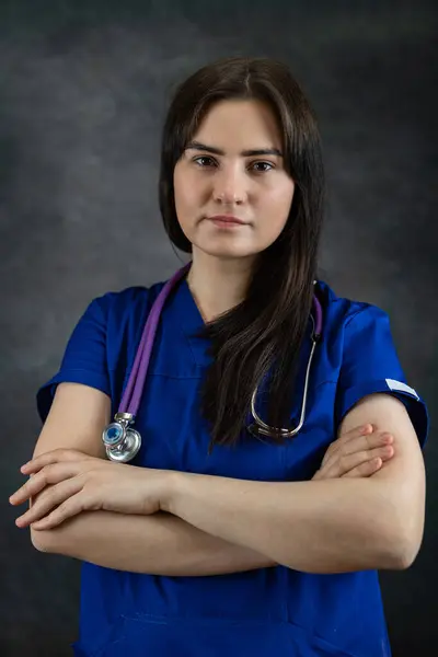 beautiful female doctor nurse  or medical student  in blue uiform with stethoscope against dark background. Medical occupation