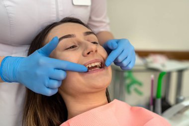 Diş aletleri olan dişi bir dişçi kadın hastasına diş temizliği yapıyor. Muayene etmek, bakıcı koruması. 