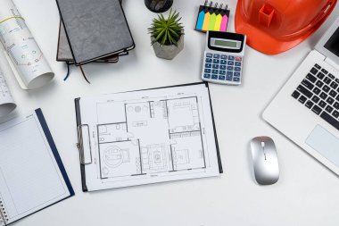 Ofis masasının üzerinde mimari plan tasarımı ve aletleri olan turuncu güvenlik kaskı. Üst Manzara. Endüstri kavramı