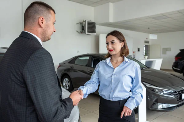 Customer buying a modern car with help a professional male manager at car dealership. concept of success deal