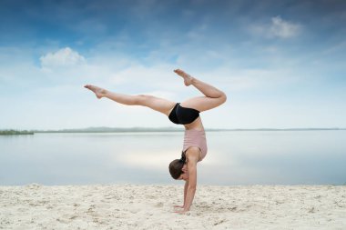 Deniz sahilinde yoga yapan beyaz kadın antrenör. Kilo verme egzersizi. Yoga ya da pilates egzersizi, sağlıklı yaşam tarzı.