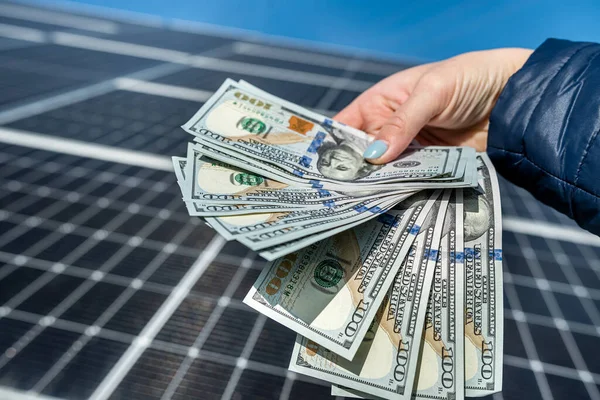 young wonderful worker is holding a round amount of money for the installation of solar panels in his hands. The concept of green electricity.