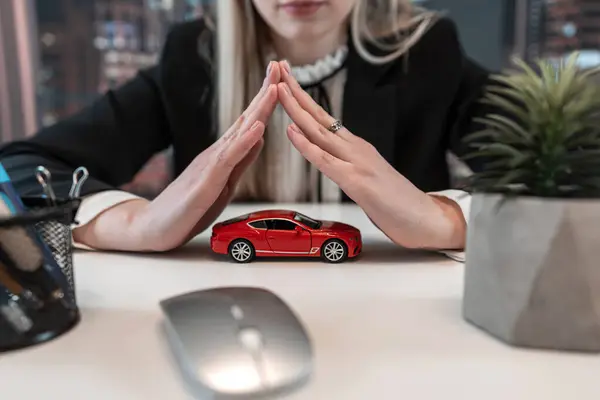 Small red toy car in the hands of business woman at office. Concept of car insurance. Rent or purchase vehicle