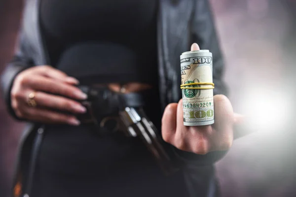 female killer hold gun pistol and stack of dollar. crime concept
