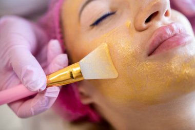 a glamorous client came for a super golden mask procedure at an expensive salon in the city. spa salon concept. facial. mask application