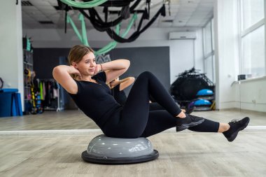 Genç sporcu kadın figürü sıkılaştırmak için dengeleyici bir minder üzerinde egzersiz yapıyor. Spor konsepti. pilates