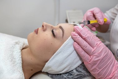 Kozmetik uzmanının kadın hasta yüzüne botoks enjekte ederek tedavi uyguladığı yakın çekim. Yaşlanma ve kırışıklık önleyici güzellik prosedürü 