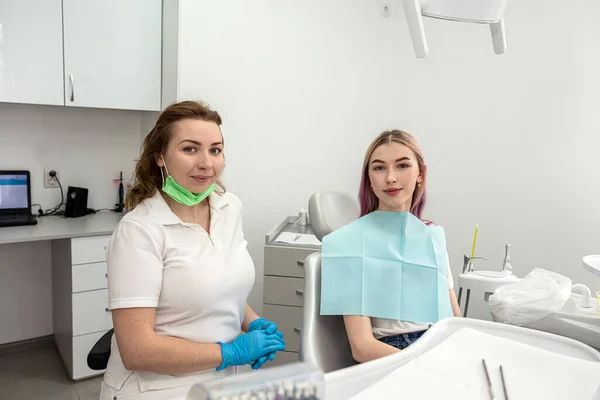 beautiful Caucasian girl is talking and consulting with a female dentist about caries and gum disease in the dental care program of a dental clinic. happy woman wants to receive care from professional