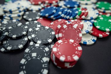 Siyah bir masaya saçılmış renkli kumarhane poker fişleri. yalnız poker. Kumarhane Kumar ya da para için oyun