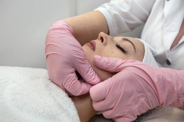 Genç bayan müşteri güzellik salonunda yüz masajı yaptırıyor. Güzellik ve cilt bakımı. 