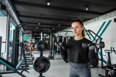 Genç bir kadın spor salonunda egzersiz makinesinde kas çalıştırıyor. Spor konsepti. Yaşam biçimi ve insanlar.