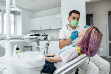 male dentist treats a girl with caries using tools. dentistry teeth healthy oral cavity. treatment. drilling teeth