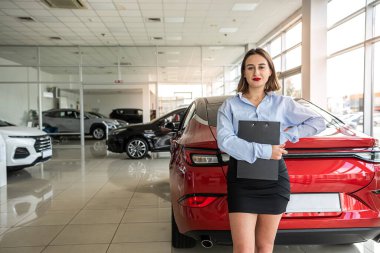 Yalnız, takım elbiseli güzel araba satıcısı yeni araba galerisinde pano tutuyor. otomobil konsepti