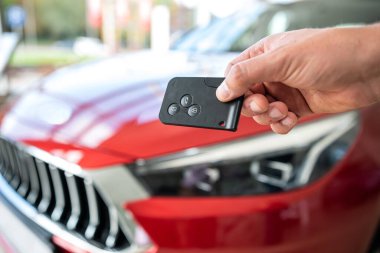 Showroom 'da yeni modern arabaya karşı erkek eliyle anahtar, başarı satışı veya kira anlaşması, ulaşım konsepti