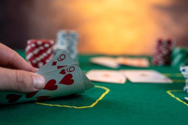 Erkek oyuncu poker oynar ve onları kolayca kaldıran kartlara bakar. Görüntüyü kapat.
