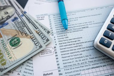 boş 1040 vergi formunun üzerinde dolar nakit kalem ve hesap makinesi. Yıllık rapor, evrak işleri