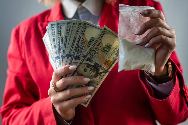 woman holding a hundred dollar bill for each dose of cocaine heroin or other drug and drugs in a bag. drugs and dollars.