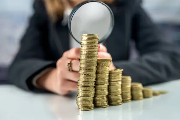 Hand with magnifying glass and money coins stack on office desk. The concept of investment business growth. saving money Investment concept. retirement concept.