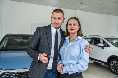an extremely happy woman is happy when her husband bought a car at a car dealership. happy couple in salon. car purchase