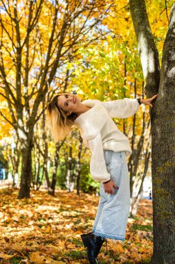 Güzel, mutlu bir gülümseme genç bir kadın sonbahar ormanında günlük giysiler giyer. Oldukça neşeli mutlu kız modeli..