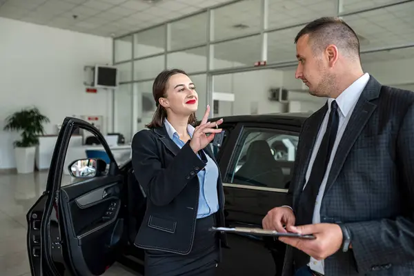 professional manager shows and taking  about car to female client in dealership, purchase concept