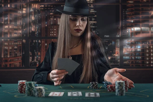 Portrait of young lady playing poker at casino. Gambling concept, night lifestyle
