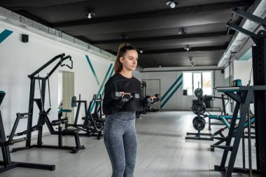 dark-haired woman in muscular shape is training her body muscles on the exercise machine in the best gym. Sport concept