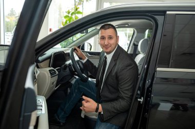 Galeride ya da galeride yeni bir araba seçen memnun, genç bir erkek müşteri. araç satışı kavramı
