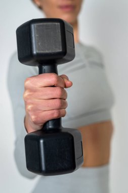 Güzel ve atletik genç bir kadın beyaz arka planda izole haldeki dambılları kaldırıyor. Harika hissediyorum. Daha da iyi görünüyor. Yaşamın sporunda