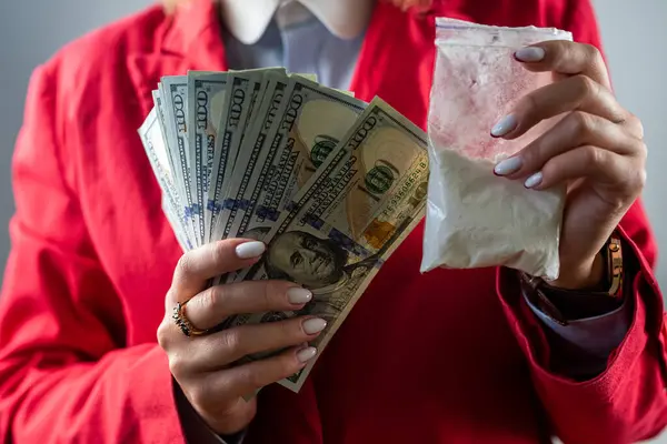 woman holding a hundred dollar bill for each dose of cocaine heroin or other drug and drugs in a bag. drugs and dollars.