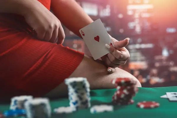 young woman in a casino in a red dress sits on a poker table with chips and cards. Poker. seductive woman