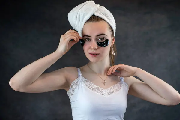 Portrait of young woman with applied black beauty patches isolated on black background. Skin care, rejuvenating