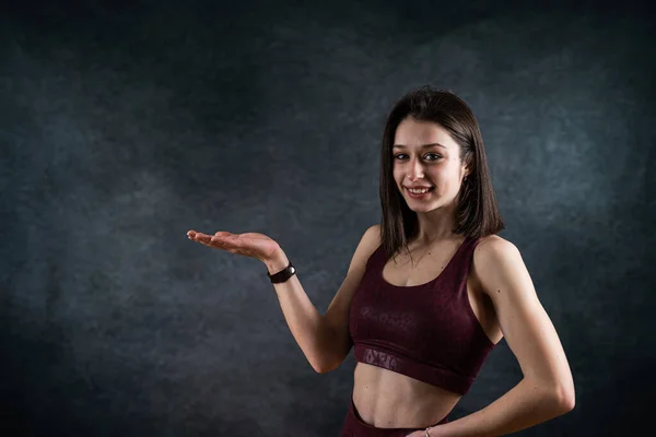 stock image Young slim female fitness trainer wearing sports bra posign at studio isolated on black. Sport fot health