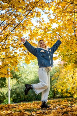 Sonbahar parkında görev yapan genç bir kadın, doğada rahatlama.