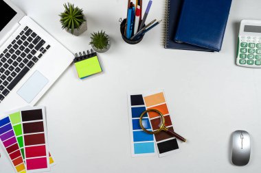 Beyaz ofis masasında kalem ve defter olan bir laptop. Düz yatış, üst görünüm