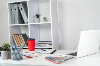 Dizayn edilmiş iş yeri dizüstü bilgisayar renk örnekleme kataloğu boş not defteri kalem ve kahve çalışma masasında. Yaratıcı çalışma, hiç kimse