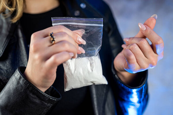 closeup of drug dealer wear black cloth hold packet of heroin or cocaine. Drug abuse concept