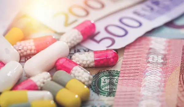 multi-colored pills on money background - euro and dollar bills. Concept of expensive cost of medicine