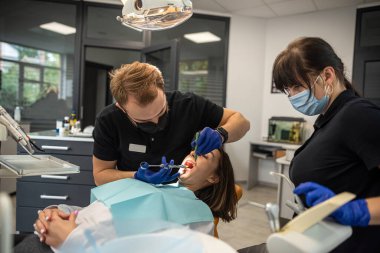 Diş hekimi ve asistanı hastayı kapsamlı bir şekilde muayene ederler. Sağlıklı diş gülümsemesi. kız