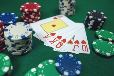 Beş poker kartında Royal Floş kombinasyonu ve kumarhane masasında cipsler. Kumar, blackjack kartları. 